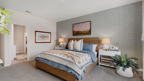 Primary bedroom with carpet, simple furnishings, and a bathroom attached.