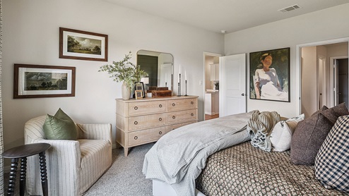 Primary bedroom with carpet, simple furnishings, and a bathroom attached.