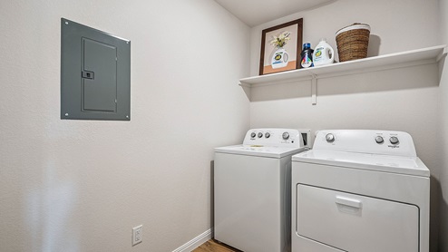 Laundry room with shelving above appliances.