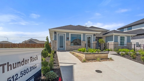 One story home with large windows and a paved walk way.