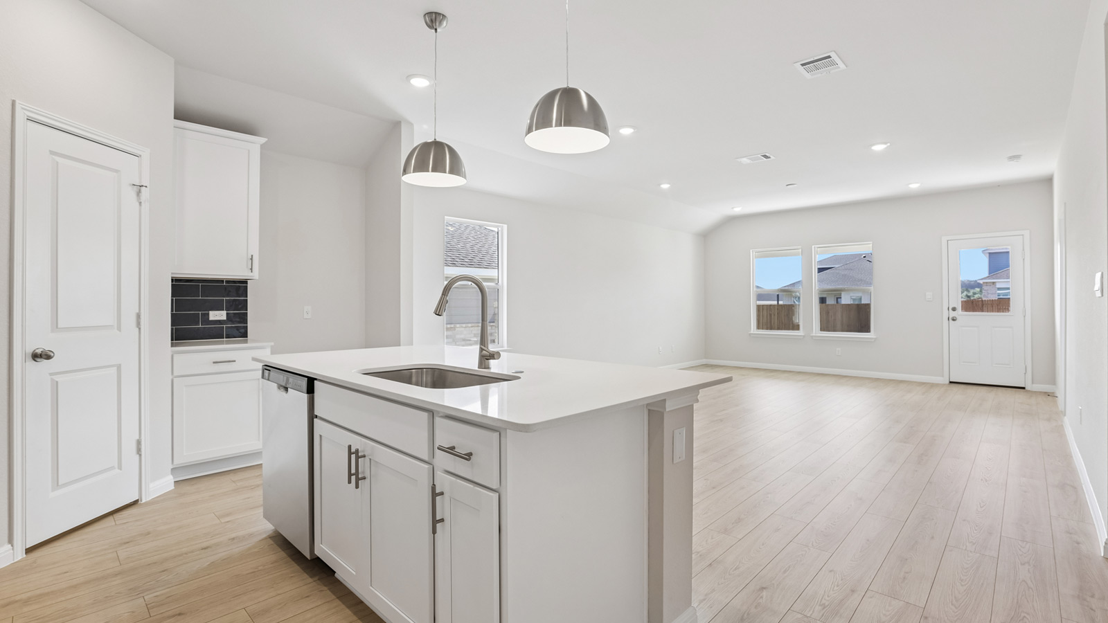 Kitchen with quartz countertops and two pendant lights over island.