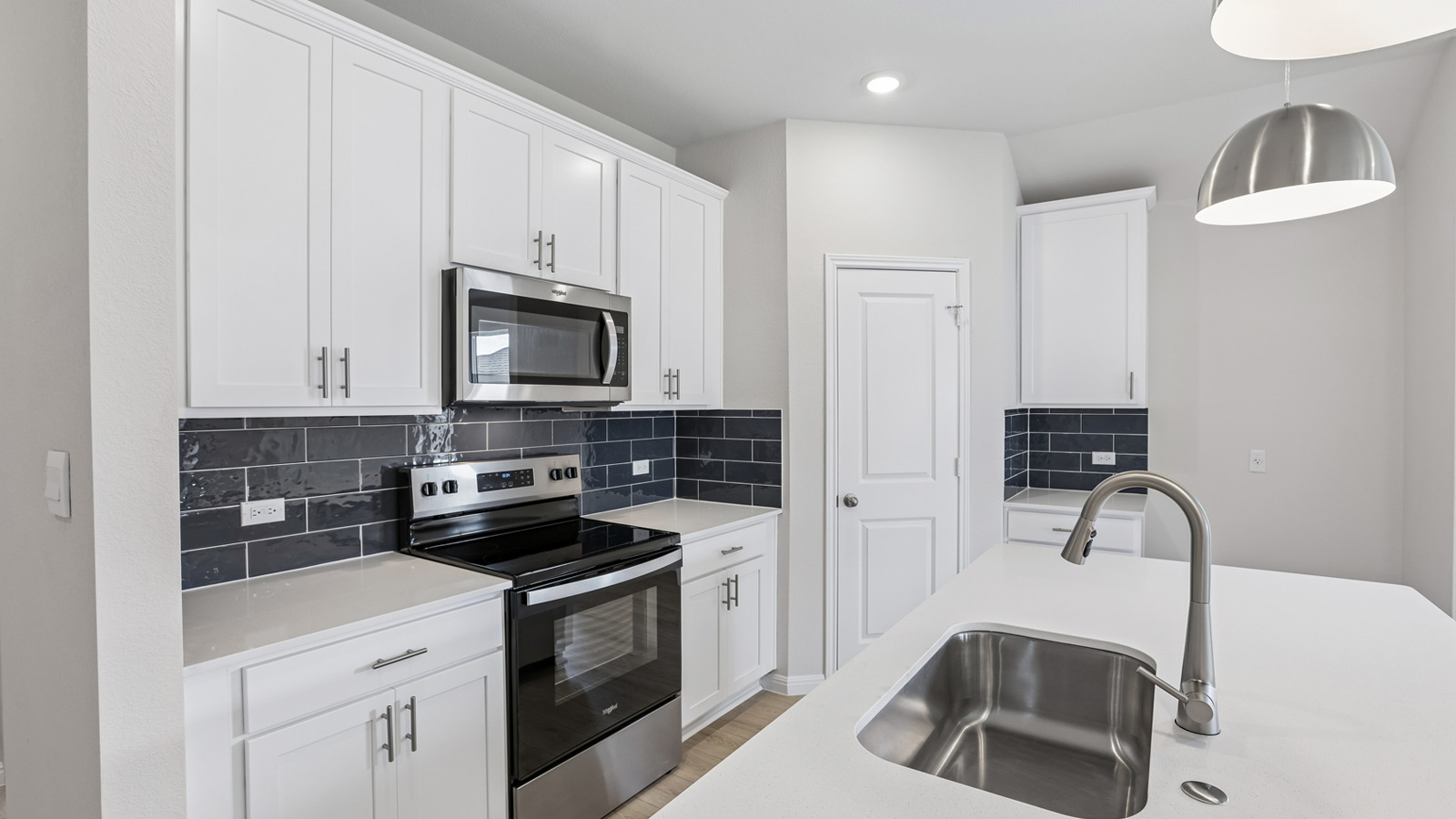 Stainless steel range, microwave and navy blue tile backsplash.
