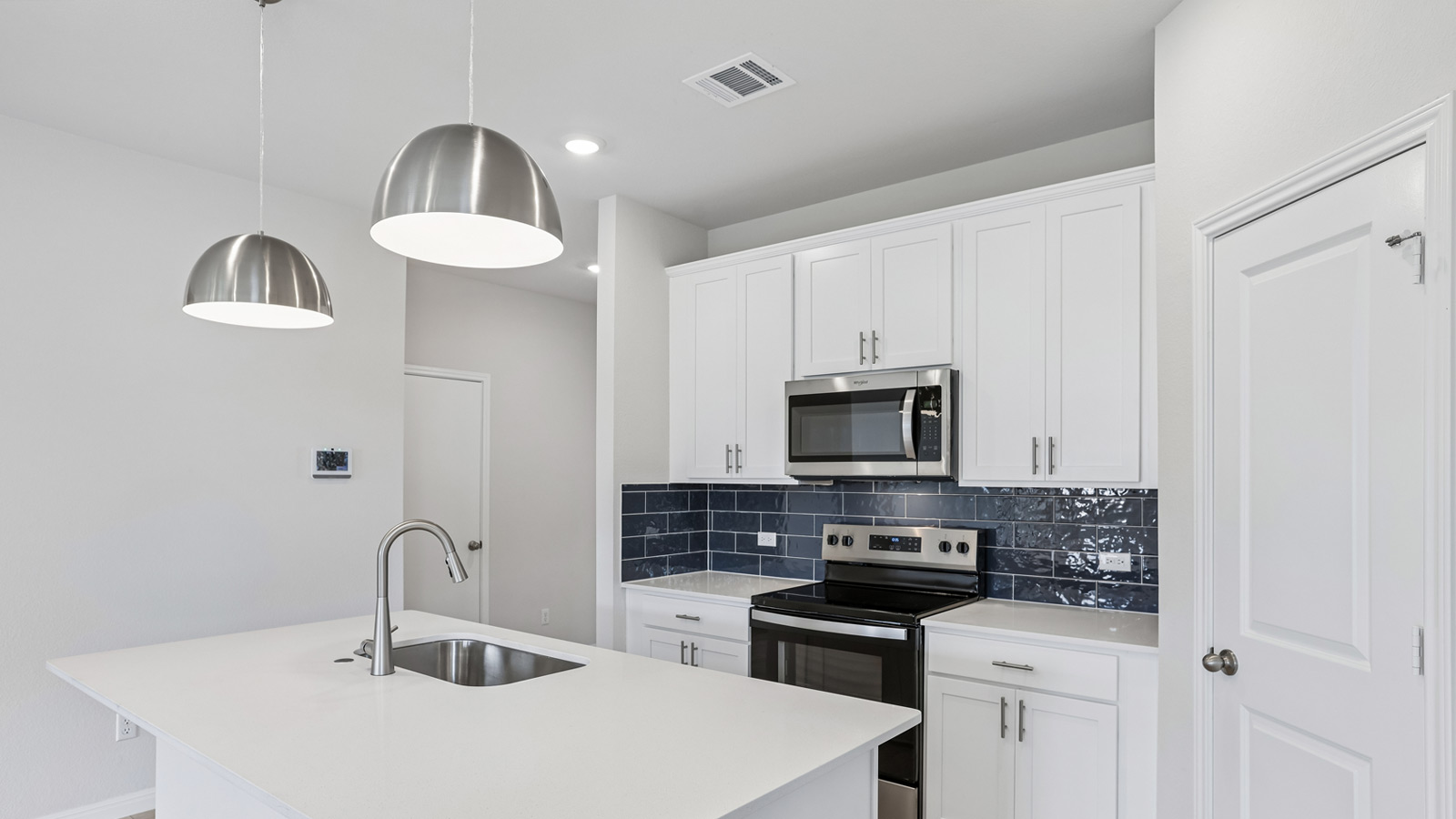 Kitchen with two pendant lights over kitchen island and tile backsplash.