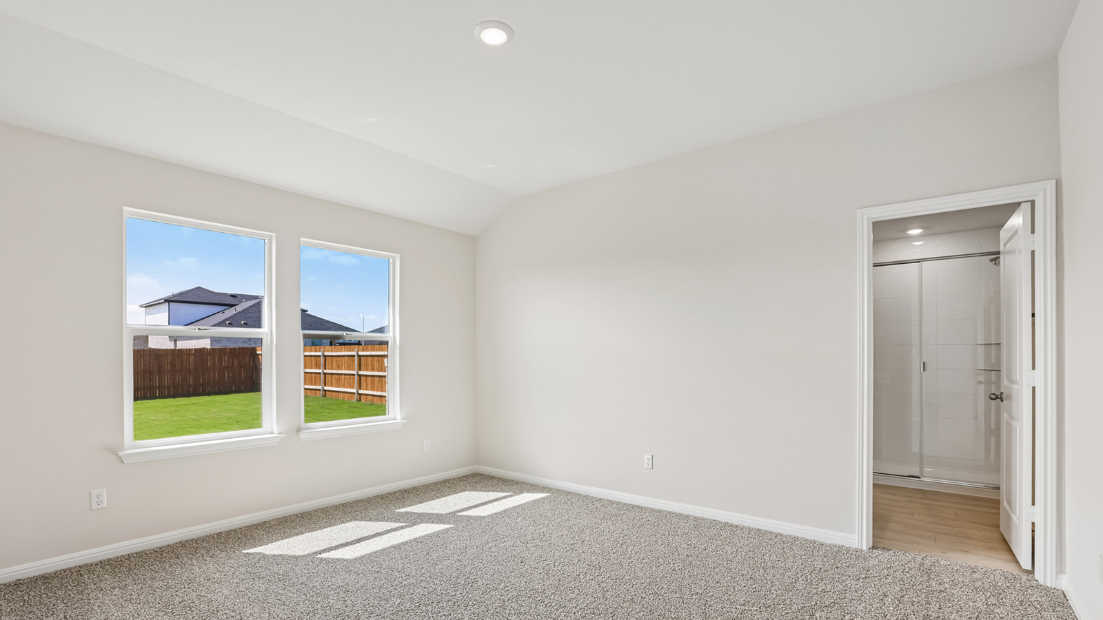 Primary bedroom with carpeted flooring and two windows.