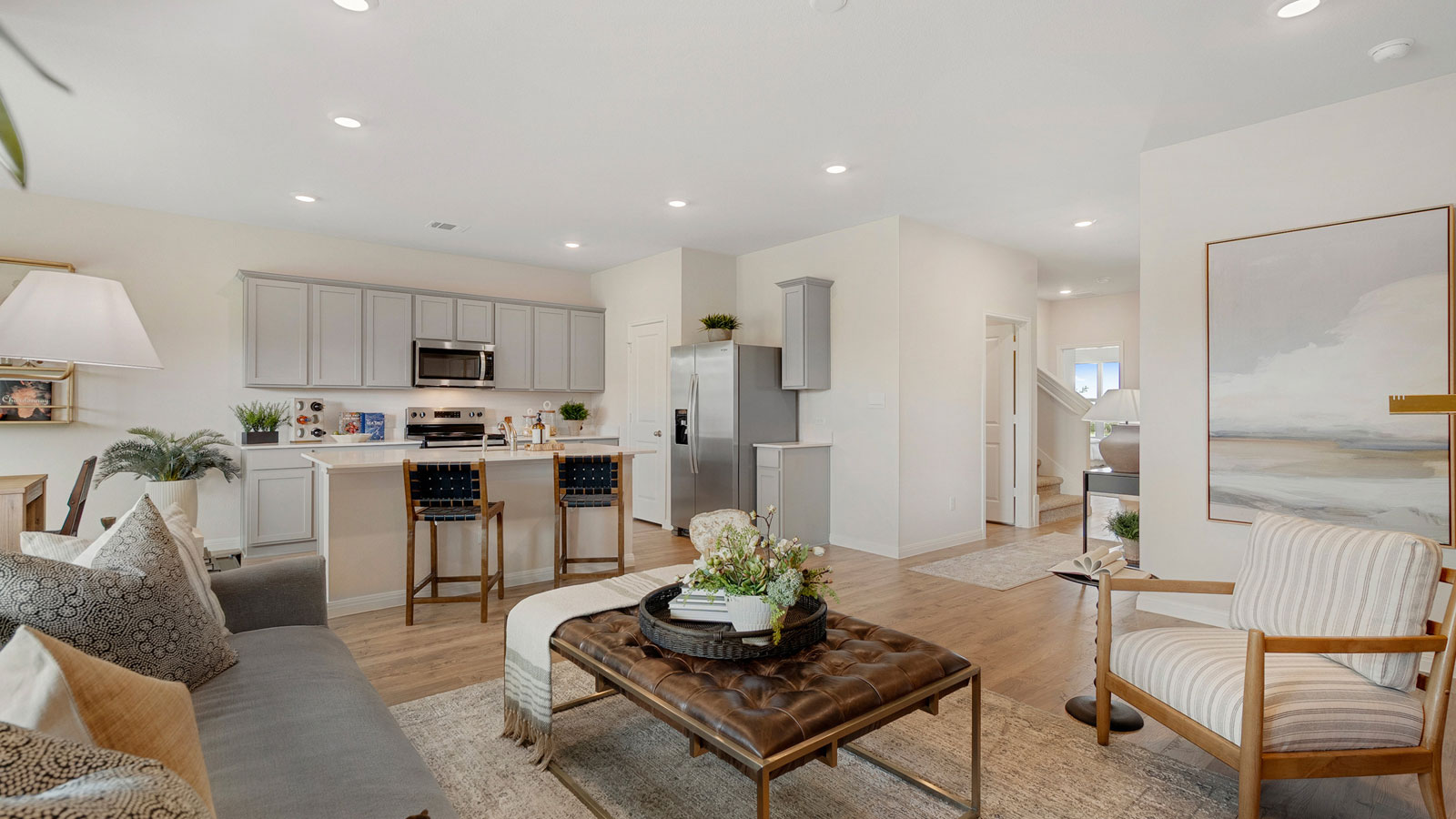 Main living area with clean flooring and natural light connecting to kitchen.