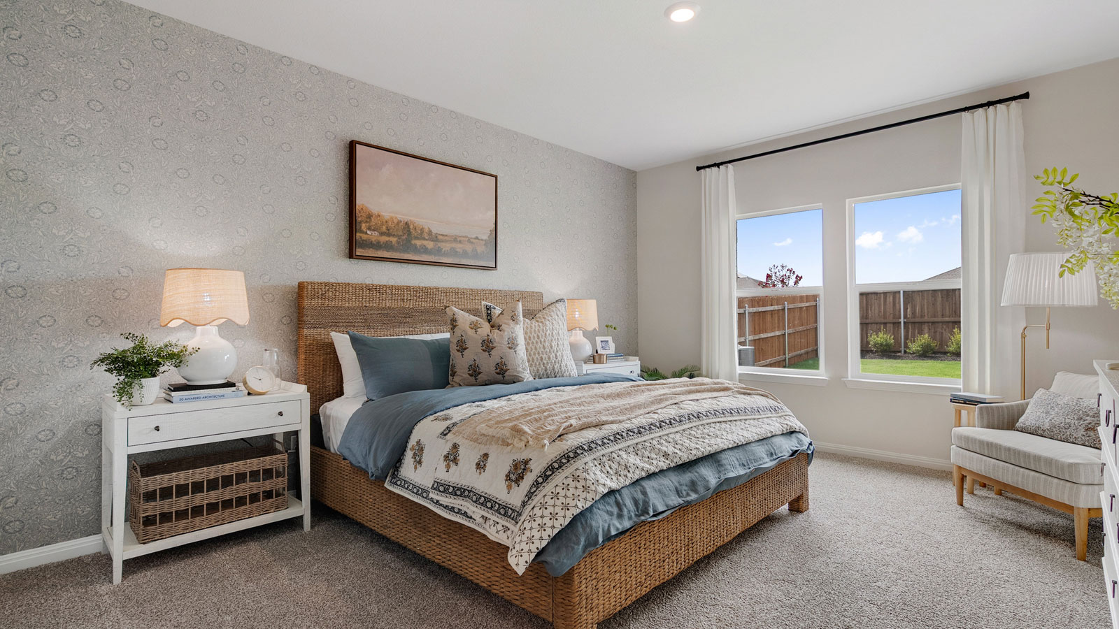Primary bedroom with carpet, large windows, and simple furnishings.