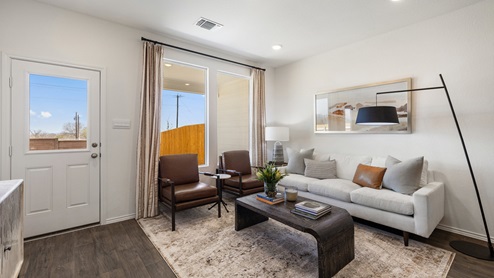 spacious living room featuring 2 large windows, 2 dark brown leather chairs and a white sofa