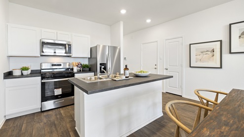 Beautiful modern kitchen with white cabinetry, stainless steel appliances and a large island