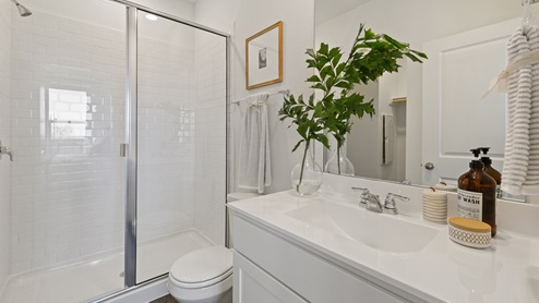 beautiful walk in shower with white subway tile, and white cabinetry