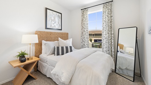 bedroom with a rattan headboard, decorated in white and black natural tones featuring a window on the right of the bed