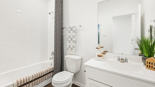 bathroom featuring a combined bathtub/shower, a toilet, and a sink with white cabinetry