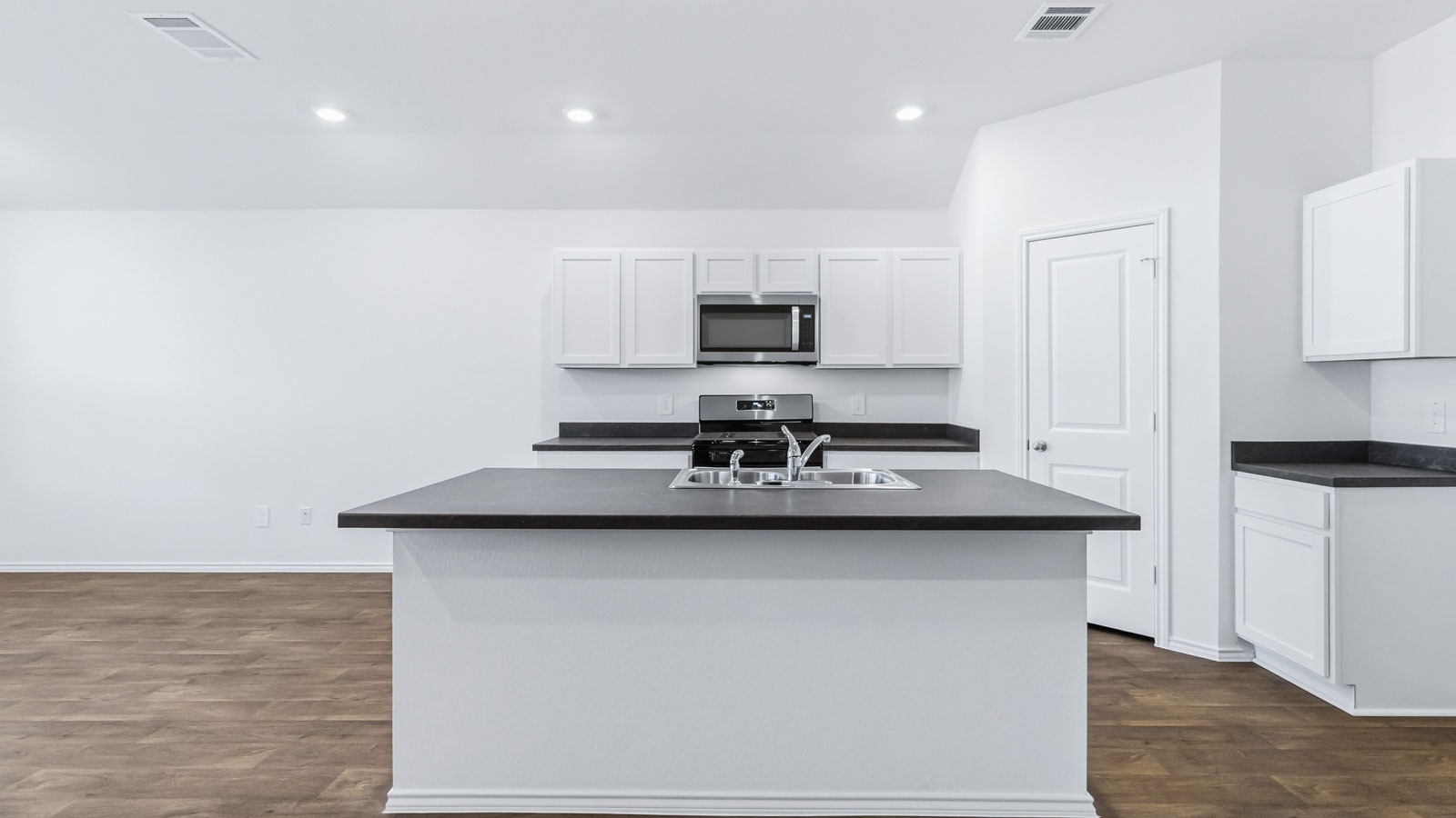 Side view of kitchen to pantry, cabinets, near dining and living areas, appliance suite included