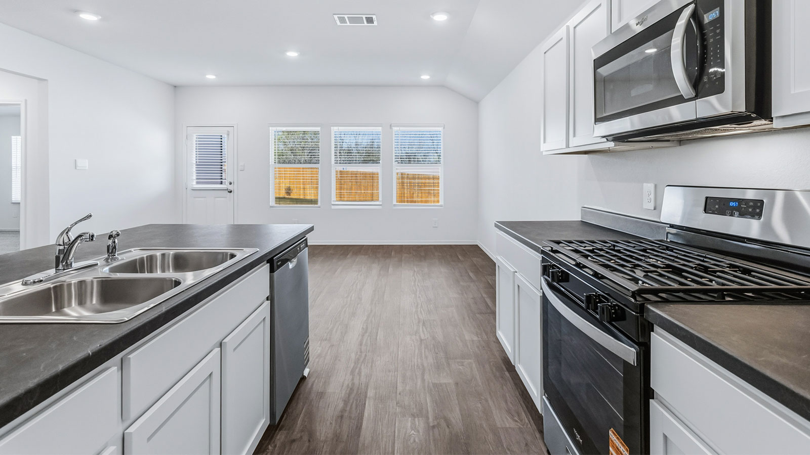 Other side view of kitchen with cabinets, dining, living areas, pantry, appliance suite included