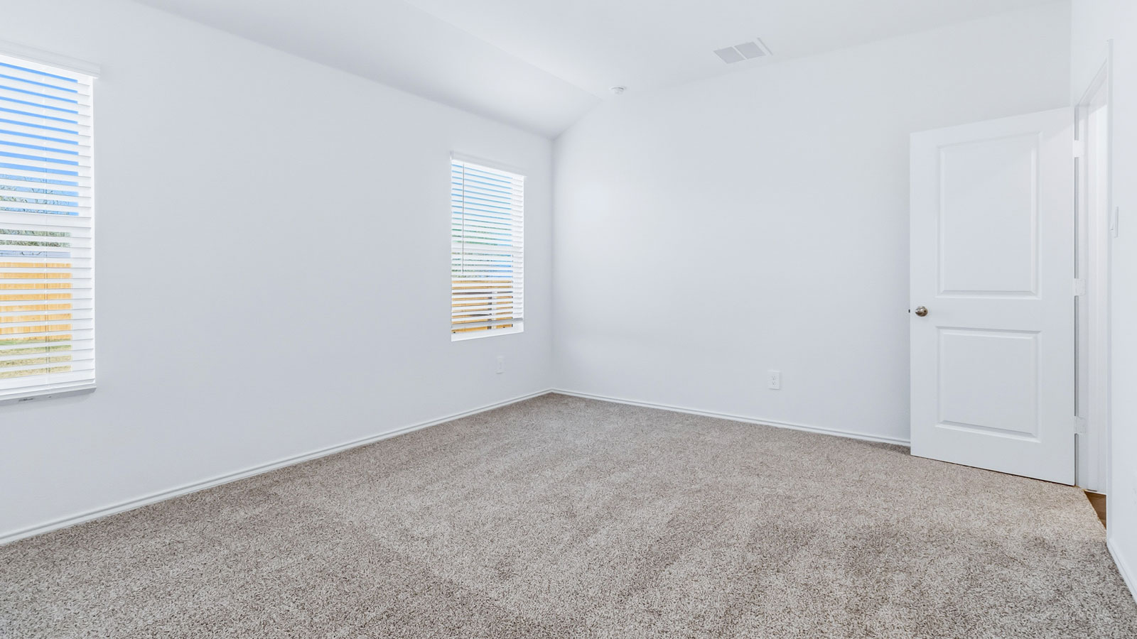 Primary bedroom features ample space, double windows, soft carpet, a stylish walk-in closet, and a private en suite bath