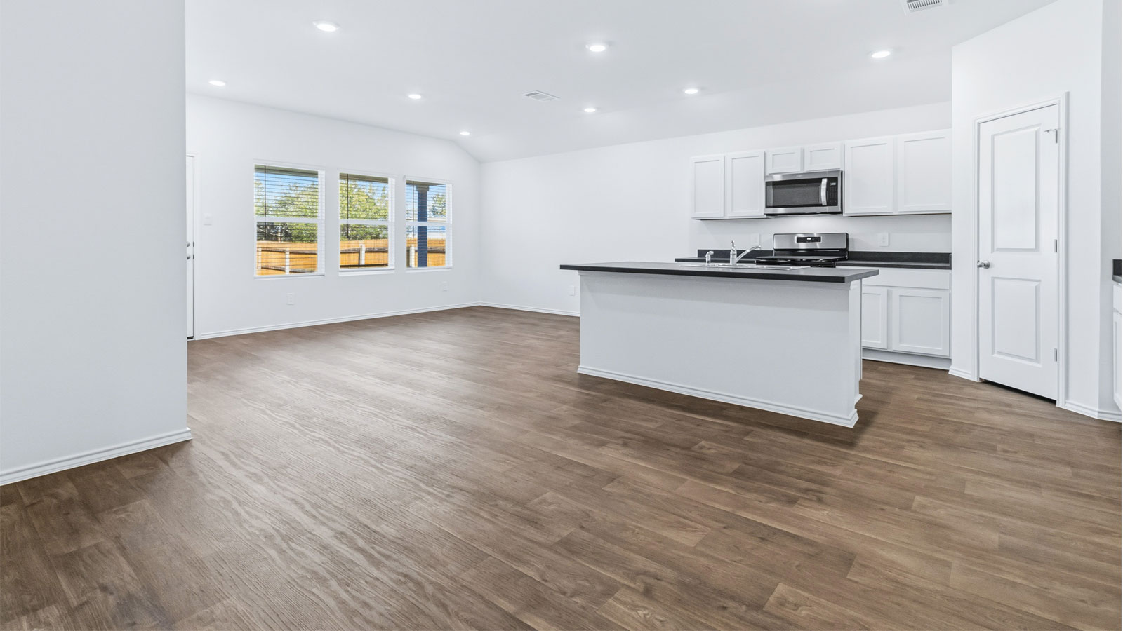 View from dining to great room, kitchen with island, pantry, appliance suite, cabinetry, outside connectivity