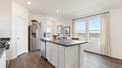 spacious kitchen with white cabinetry, stainless steel appliances, large kitchen island, and 2 large windows bringing in natural light