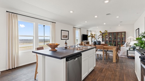 spacious kitchen with white cabinetry, stainless steel appliances, large kitchen island, and 2 large windows bringing in natural light