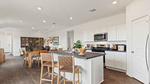 spacious kitchen with white cabinetry, stainless steel appliances, large kitchen island, and 2 large windows bringing in natural light