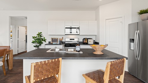 spacious kitchen with white cabinetry, stainless steel appliances, large kitchen island, and 2 large windows bringing in natural light