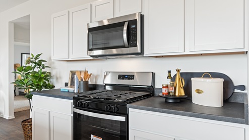 spacious kitchen with white cabinetry, stainless steel appliances, large kitchen island, and 2 large windows bringing in natural light