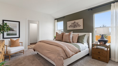 Primary bedroom with an olive green accent wall behind the king bed. This bedroom features light orange and green decor