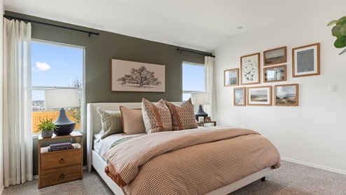 Primary bedroom with an olive green accent wall behind the king bed. This bedroom features light orange and green decor