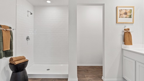 Modern bathroom featuring rich brown floors, white cabinetry and a large mirror