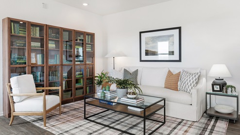 Spacious living room decorated in natural wood tones, white couches and touches of greenary
