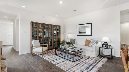 Spacious living room decorated in natural wood tones, white couches and touches of greenary
