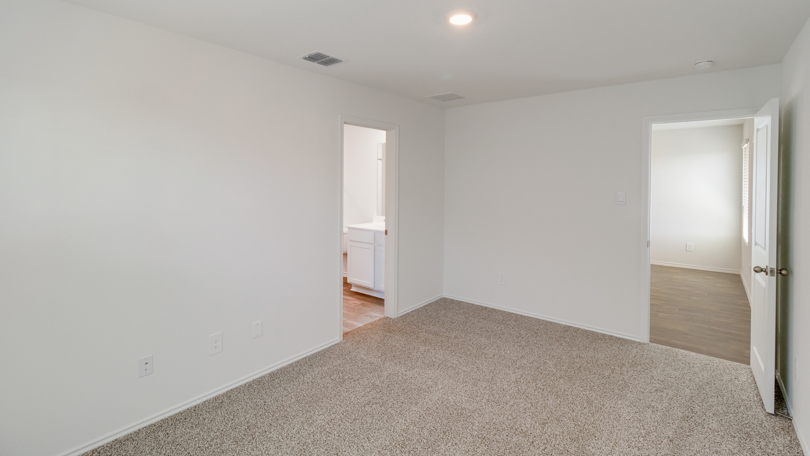 Primary suite at Wayside includes corner window views, walk-through access to an en suite bathroom, walk-in closet