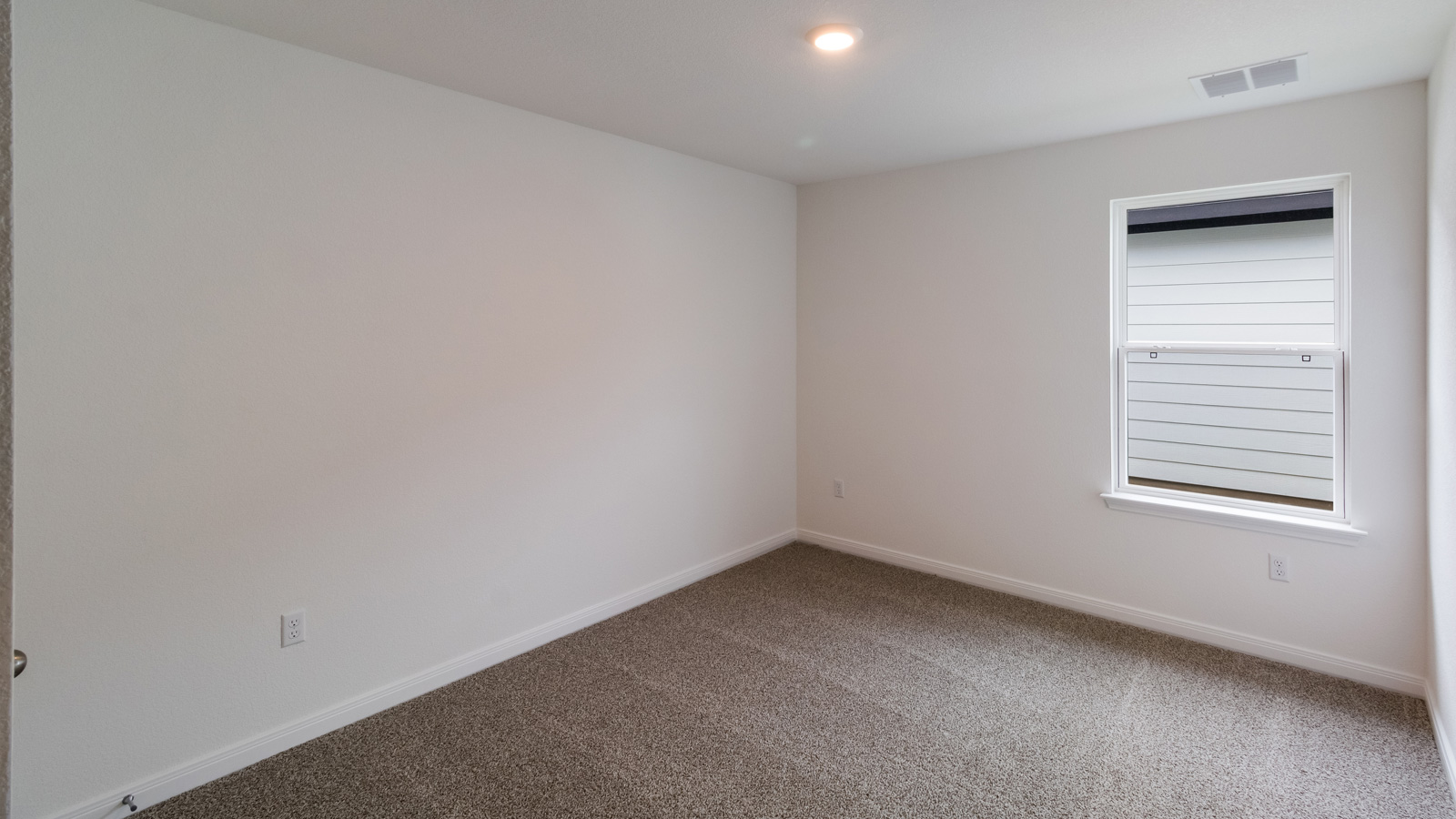 bedroom with beige carpet, white walls and a window