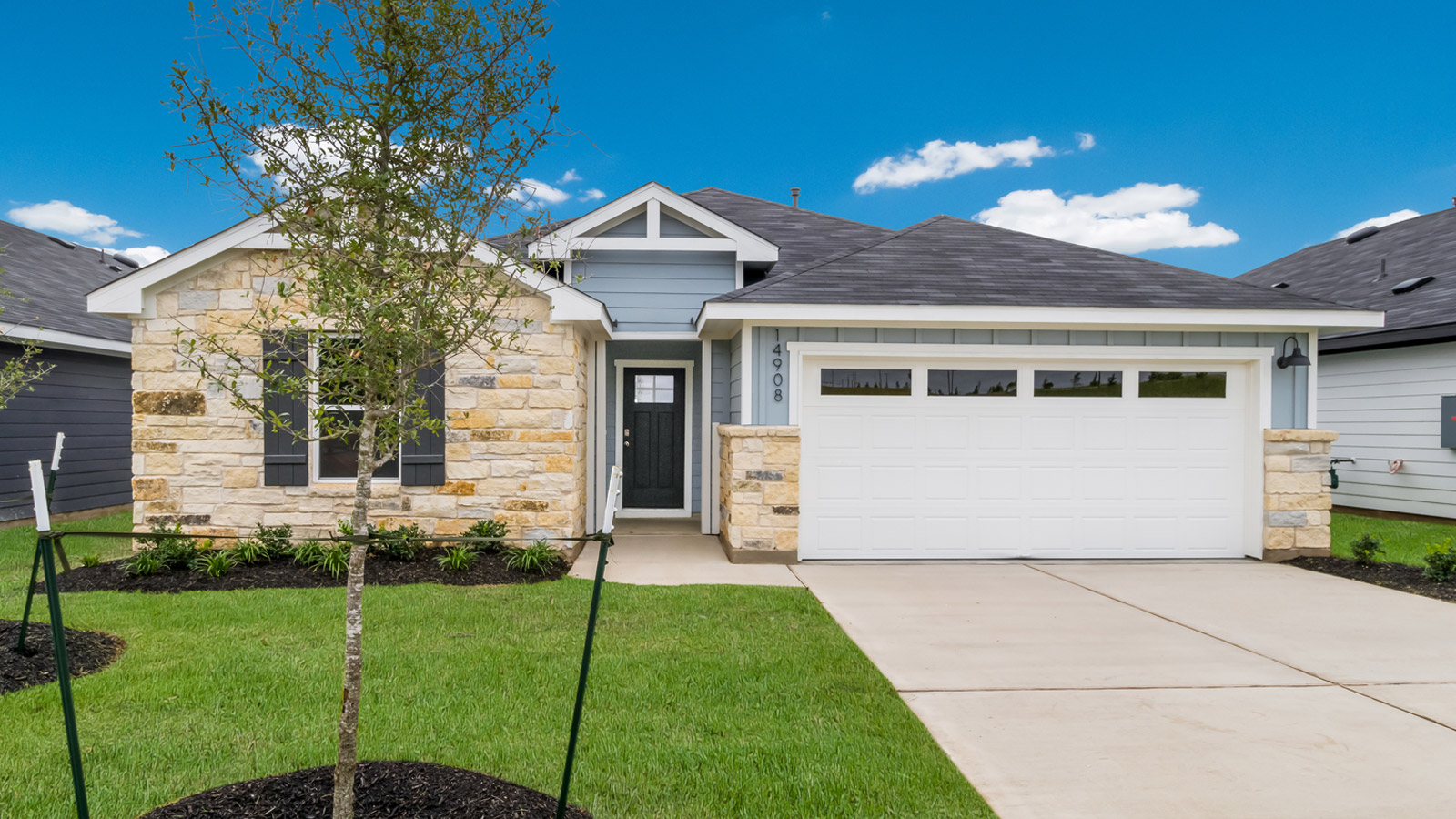 front exterior of a one story home with light blue siding and stone accents