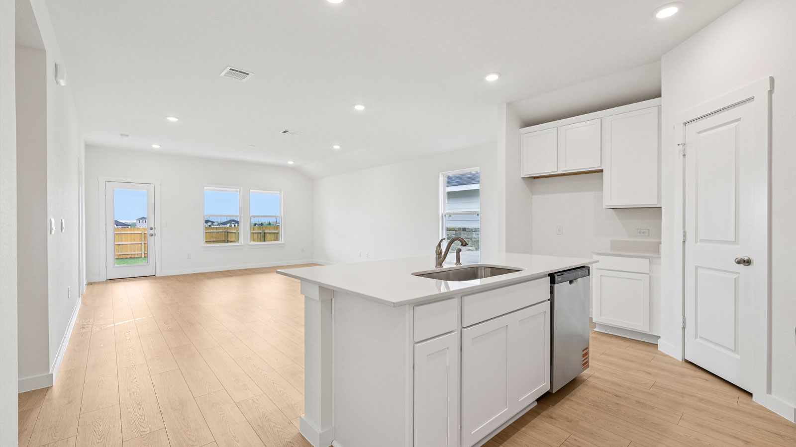 Open concept kitchen and living area with windows overlooking backyard.