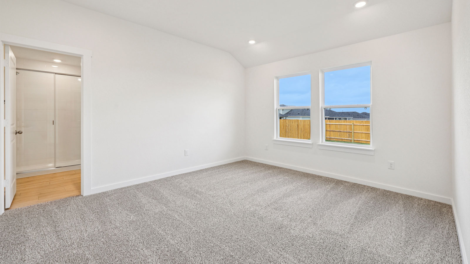 Primary bedroom with carpeted flooring and large window.