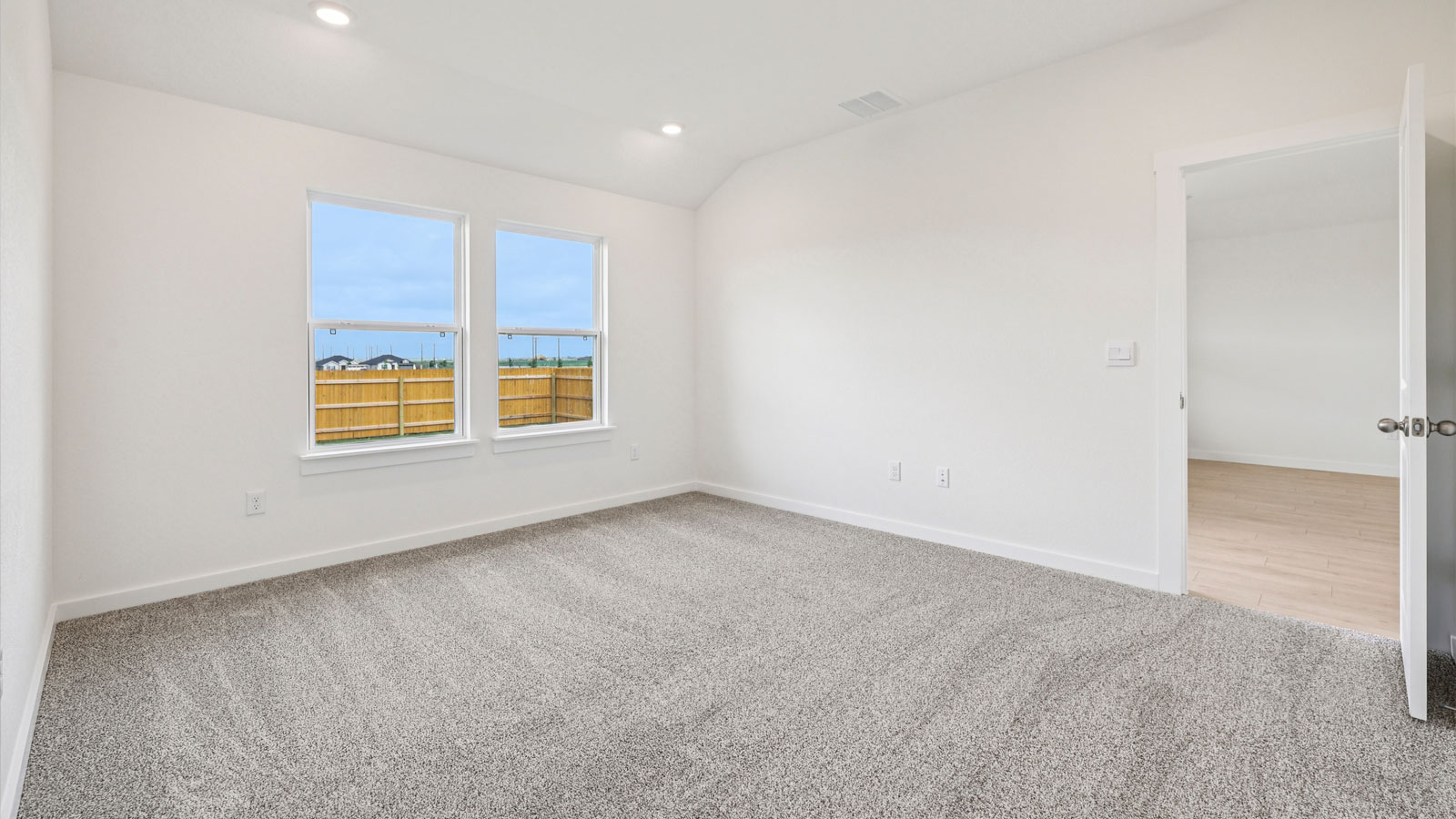 Primary bedroom with carpeted flooring and large window.
