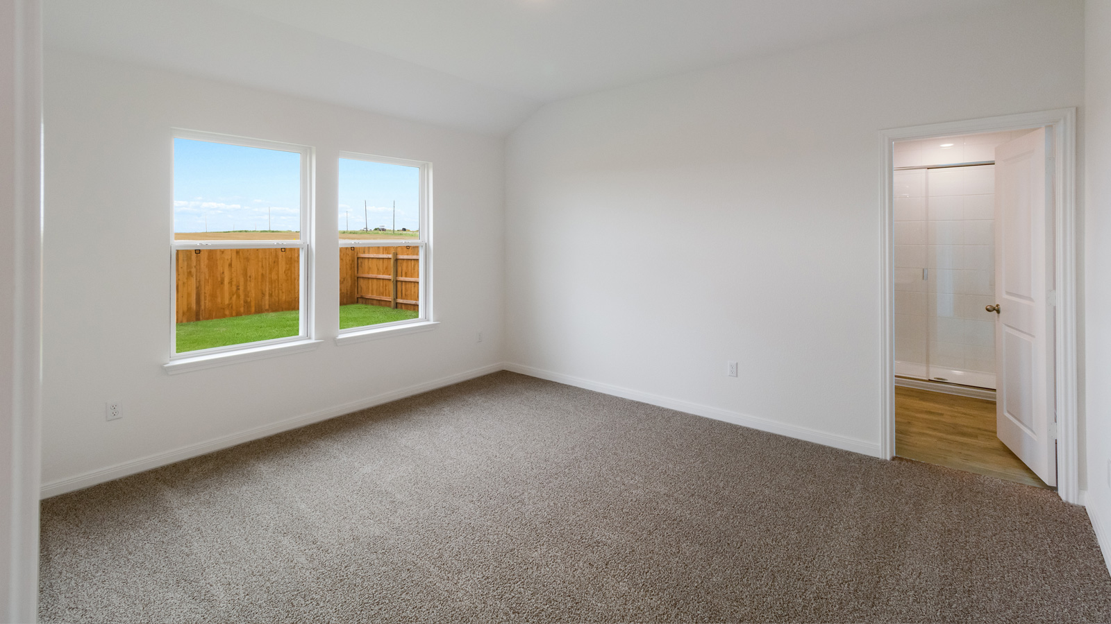 bedroom with beige carpet, white walls and a window