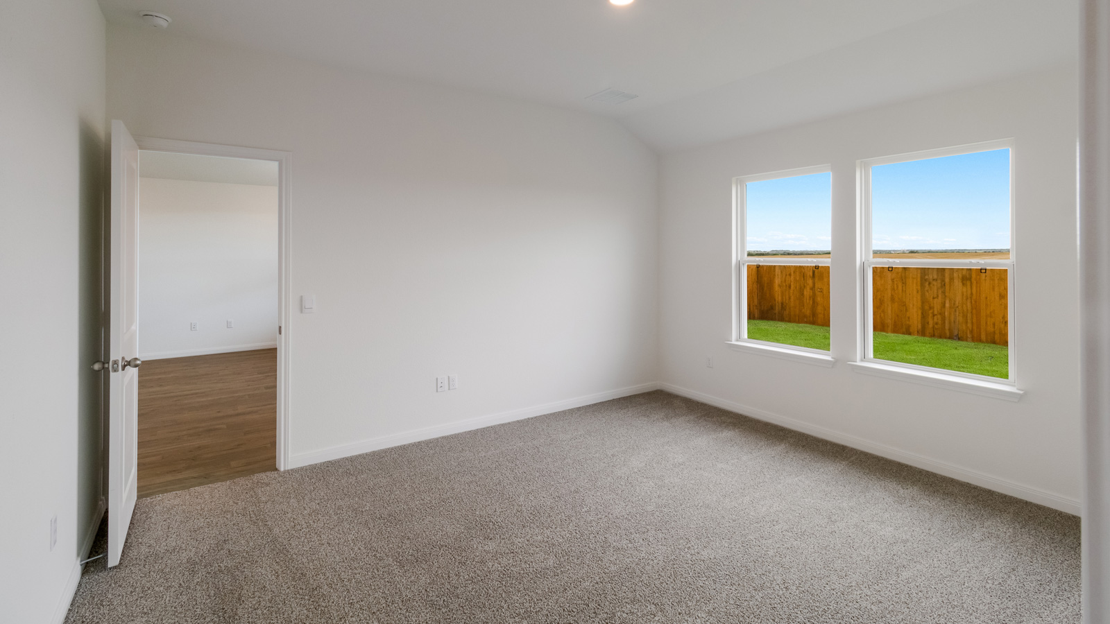 bedroom with beige carpet, white walls and a window