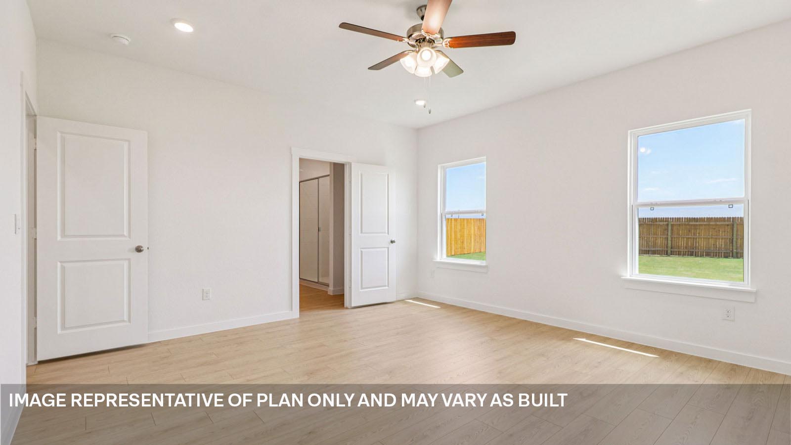 Primary bedroom with two windows and laminated wood plank flooring.