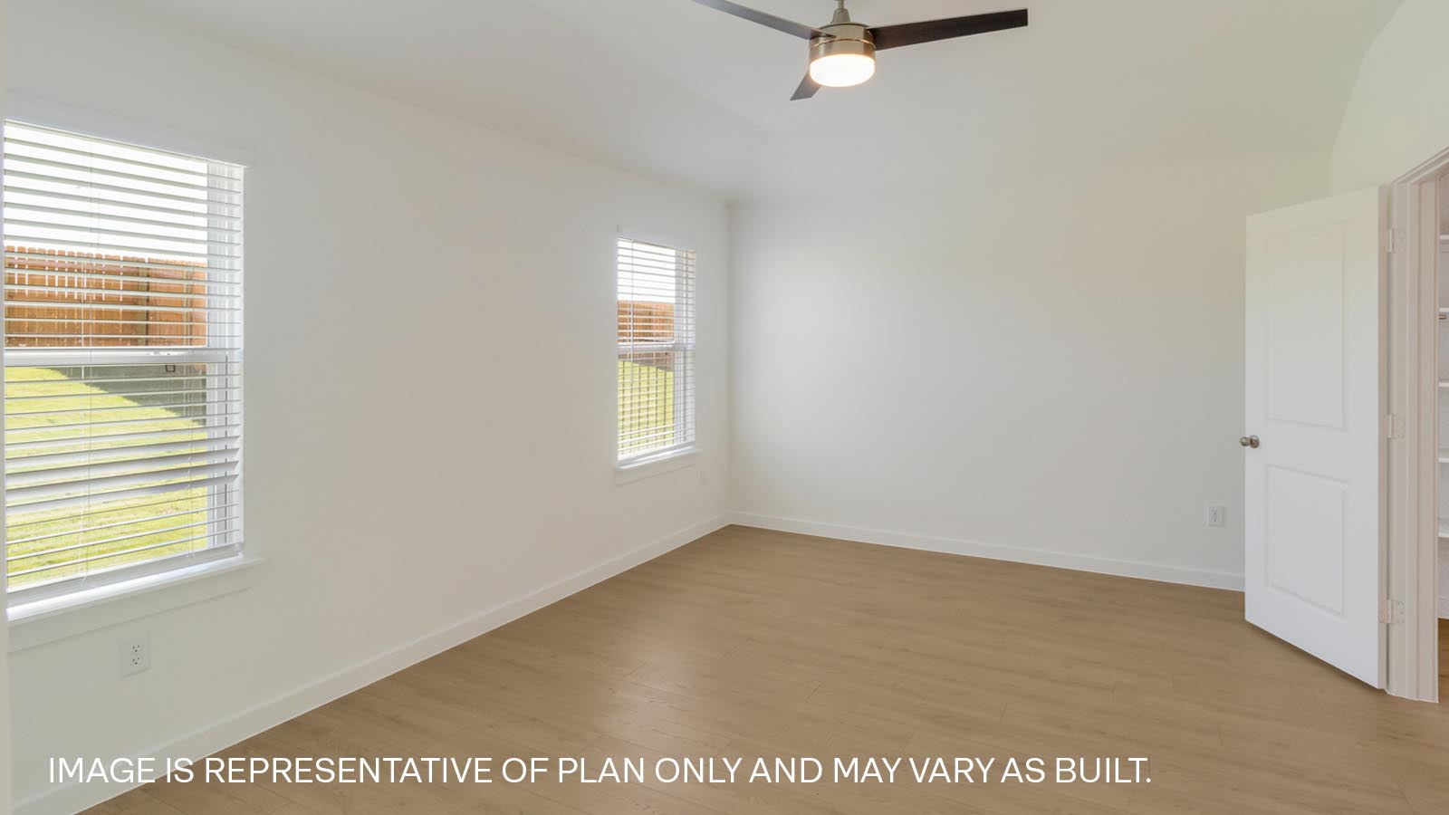 Spacious primary bedroom with two windows and ceiling fan.