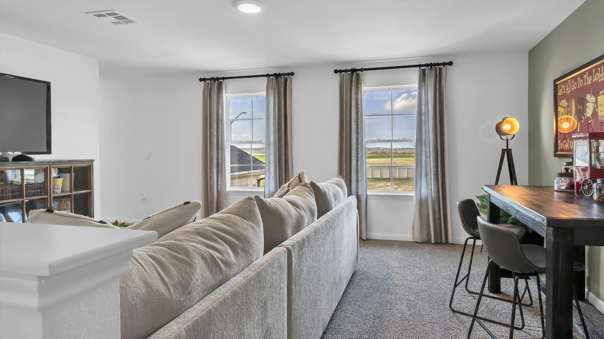 upstairs flex room with a beige sectional, and a tv