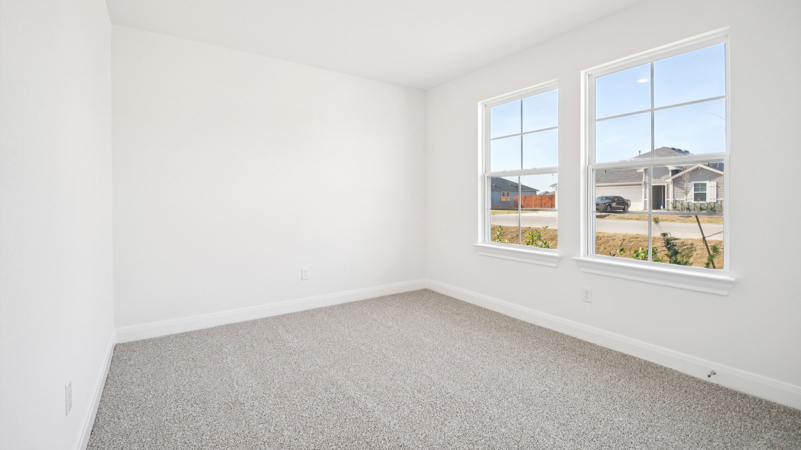 Bedroom 2 with carpeted flooring and large windows.