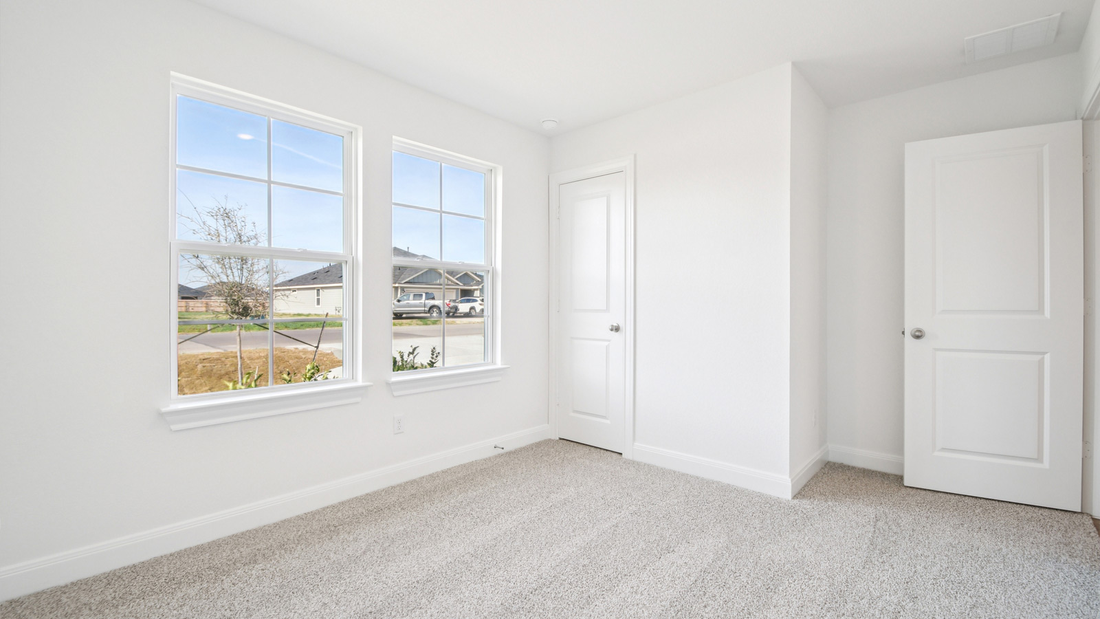 Bedroom 2 with carpeted flooring and large windows.