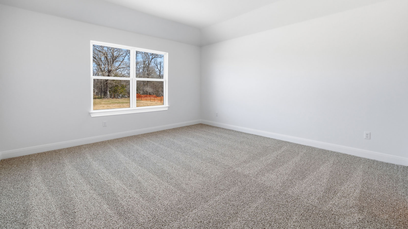 Primary bedroom with carpeted flooring and window.