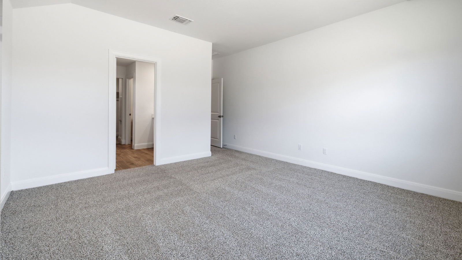 Primary bedroom with carpeted flooring and window.