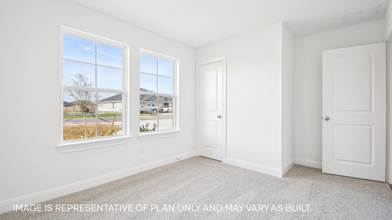Bedroom 2 with carpeted flooring and large windows.