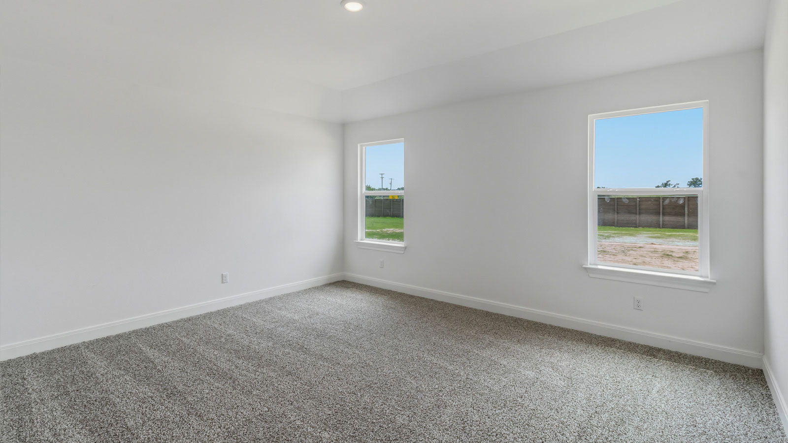 Primary bedroom with two windows and carpeted flooring.