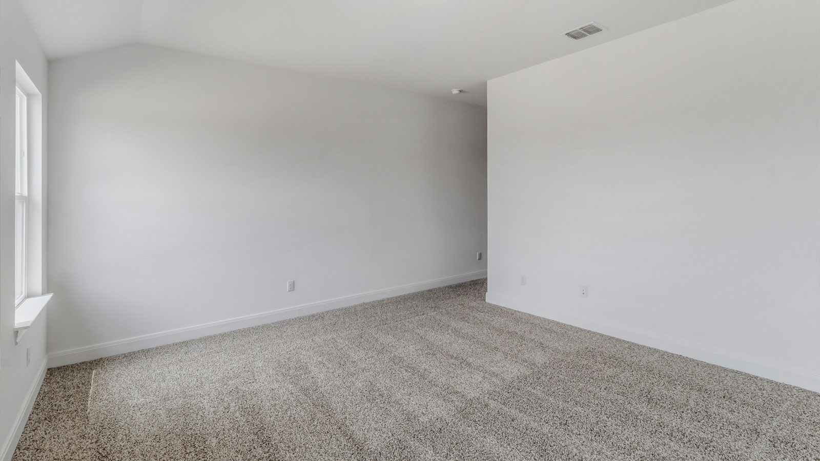 Primary bedroom with two windows and carpeted flooring.