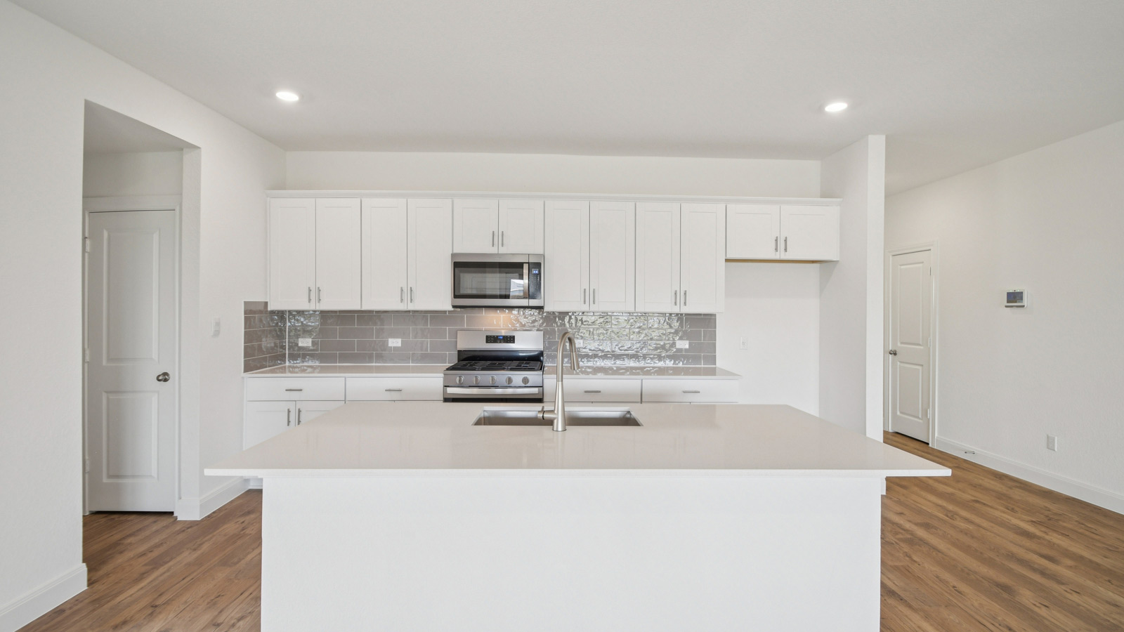 Gourmet kitchen with quartz countertops and decorative tile backsplash.