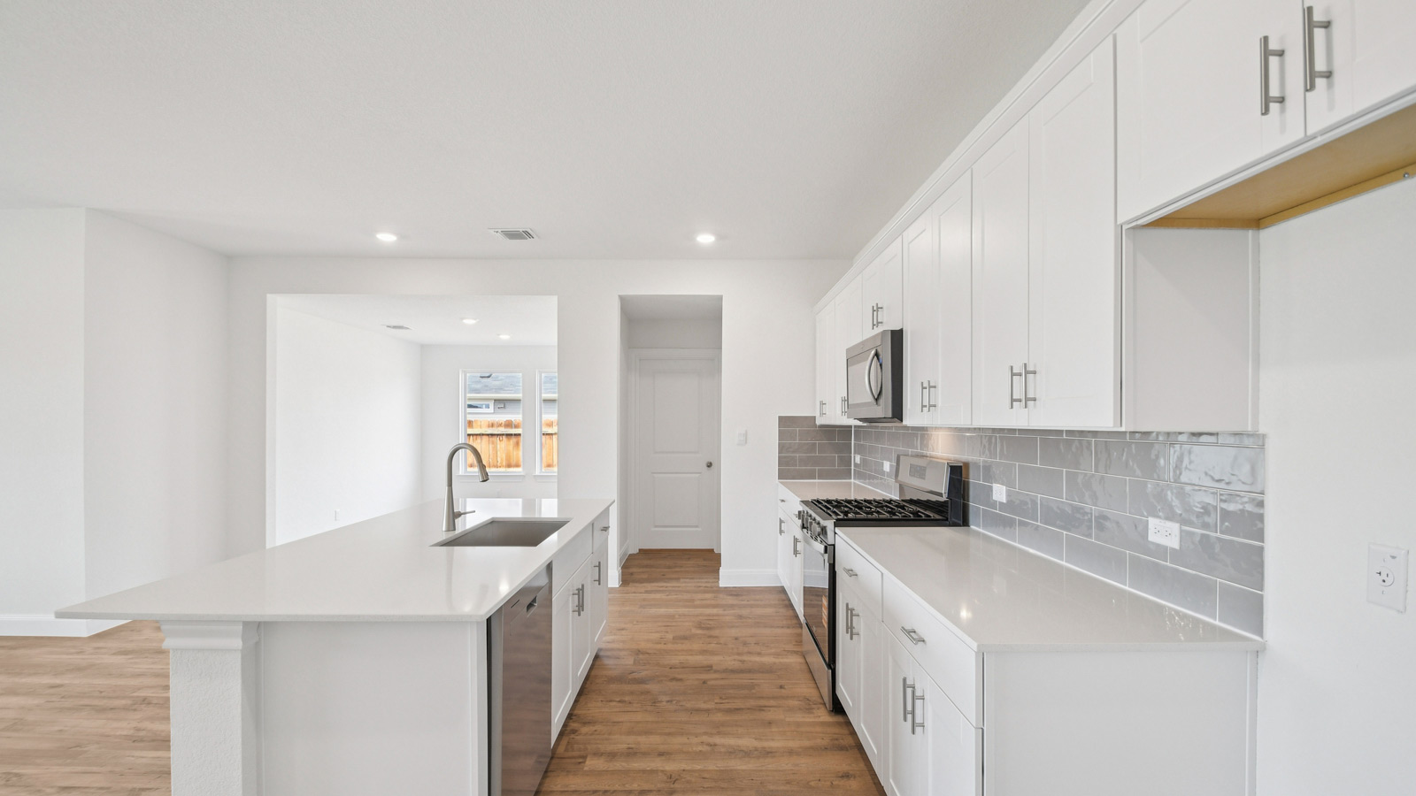 Gourmet kitchen with quartz countertops and decorative tile backsplash.