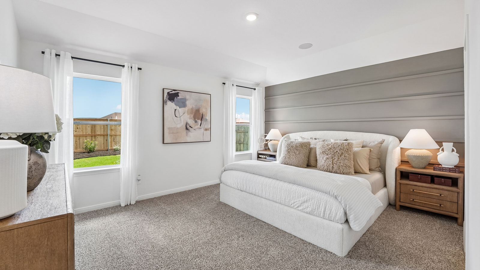 Spacious primary bedroom with carpeted flooring and large windows.